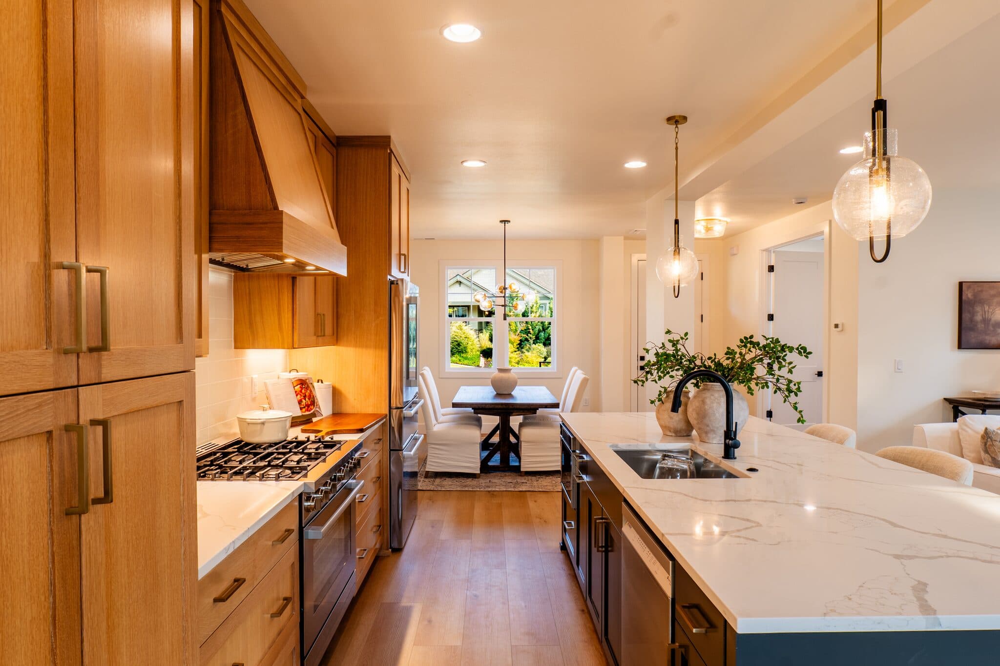 Long kitchen with wood cabinets and dining nook — real estate photography by Hahn Media, Oregon